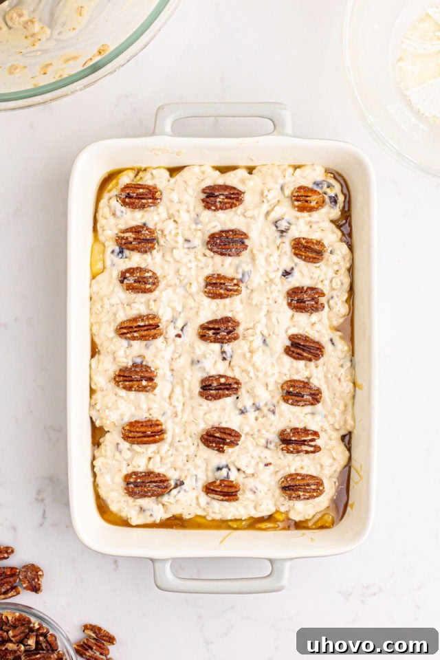 Overhead view of the unbaked cobbler, now adorned with pecan halves scattered over the crust, ready for baking.