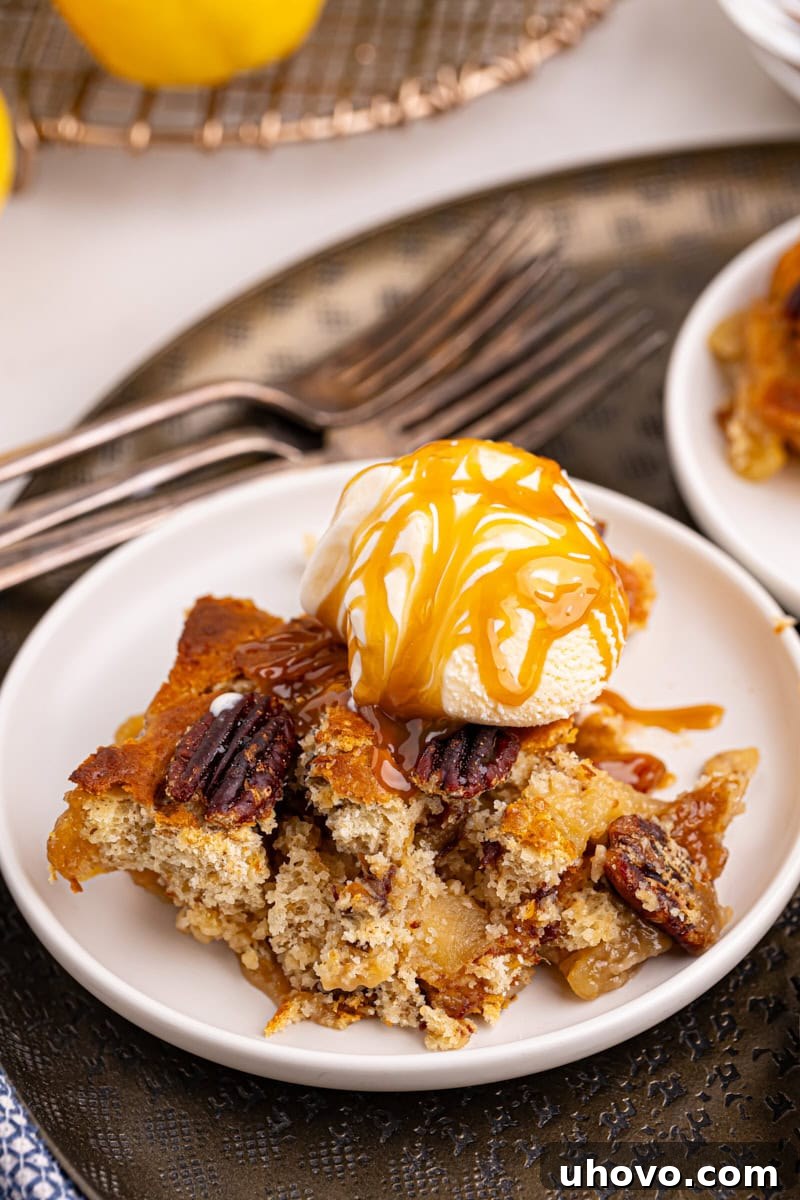 A stunning close-up of a serving of caramel apple pear cobbler, elegantly presented with a melting scoop of vanilla ice cream and a luscious swirl of caramel sauce, highlighting its textural appeal.