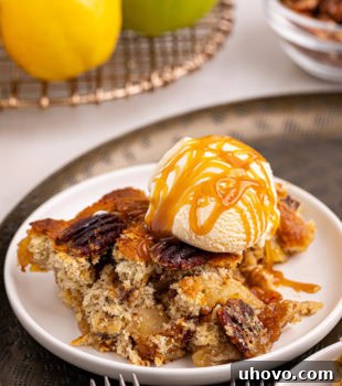 A serving of caramel apple pear cobbler topped with vanilla ice cream and caramel sauce in a white bowl