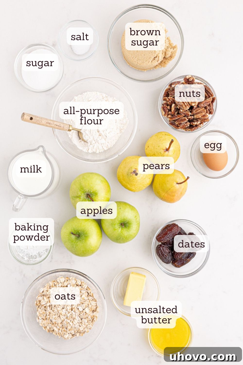 Overhead view of various fresh ingredients laid out on a wooden surface, including sliced apples, pears, flour, brown sugar, oats, and butter, ready for making caramel apple pear cobbler.
