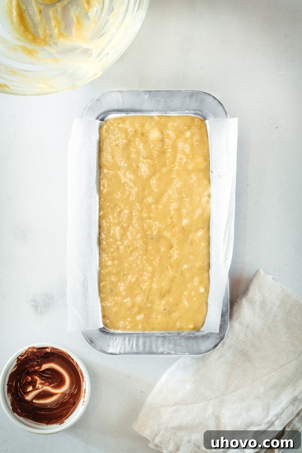 Overhead view of the completed banana bread batter in the loaf pan, with the final Nutella swirls visible on top, showcasing its readiness for baking.