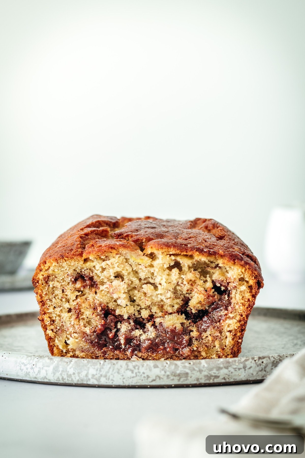 A perfectly cut loaf of Nutella Banana Bread resting on a rustic wooden board, showing the tempting Nutella swirls and moist texture, ready to be served and enjoyed by everyone.