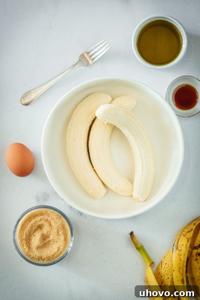 Overhead view of three perfectly ripe bananas in a mixing bowl, ready to be mashed for the banana bread batter.
