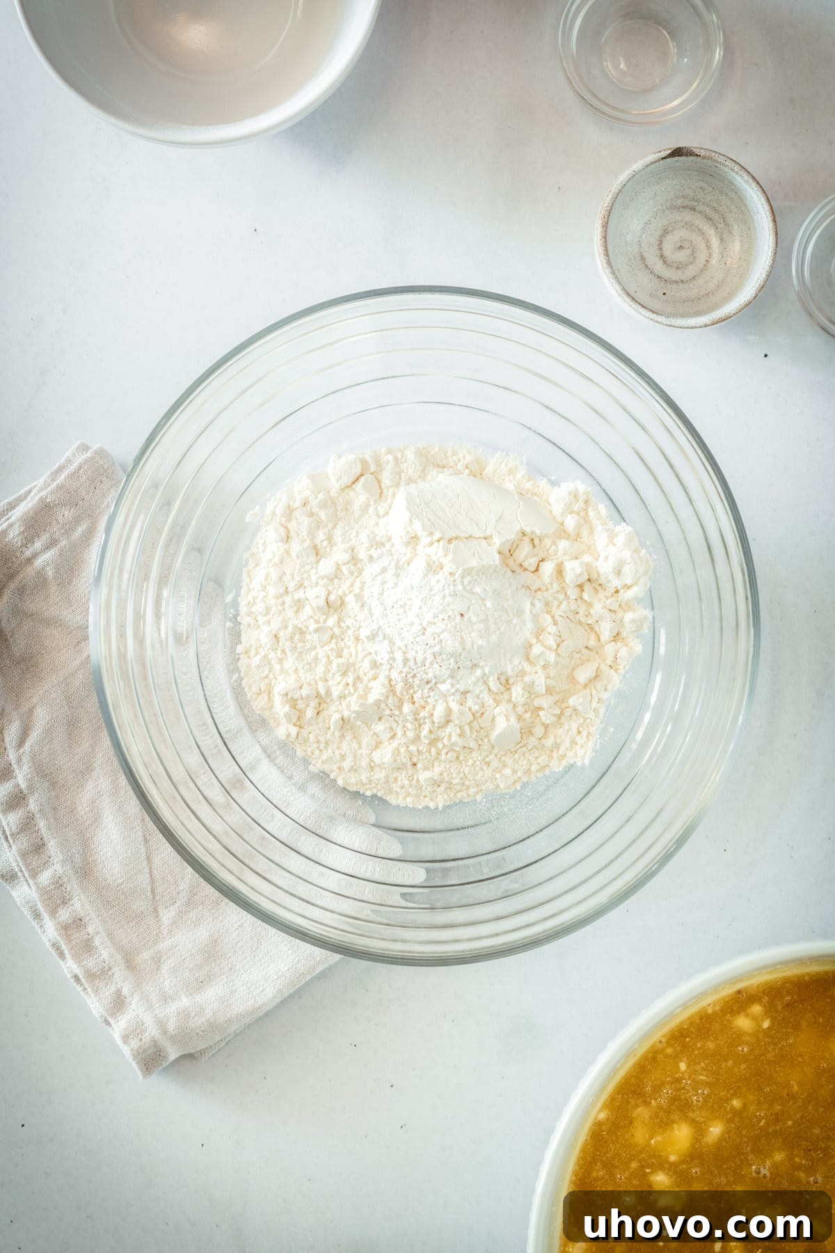 Overhead view of all the dry ingredients, including flour, baking powder, baking soda, and salt, perfectly combined and whisked in a glass mixing bowl.