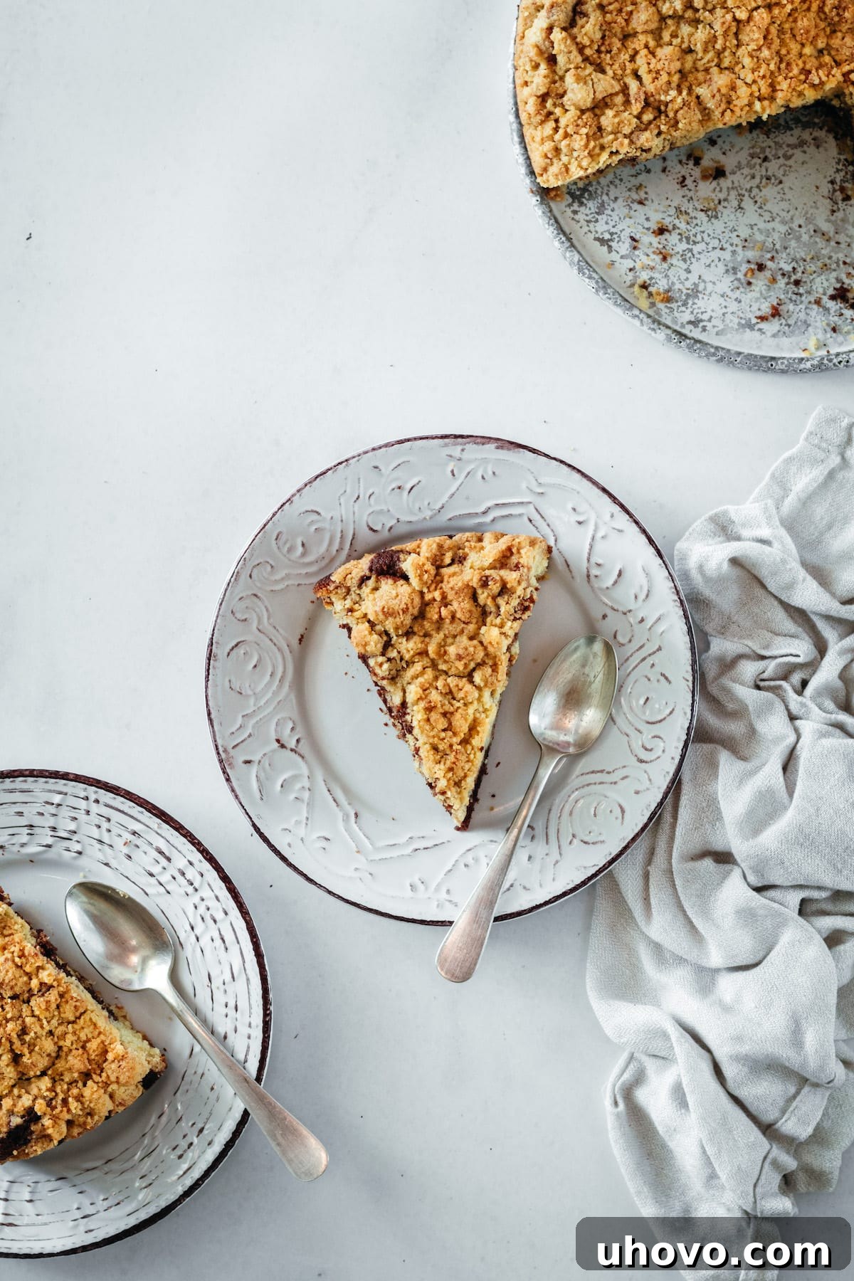 Overhead view of two plates with slices of coffee cake and spoons, with the remaining coffee cake in the background, ready to be enjoyed.