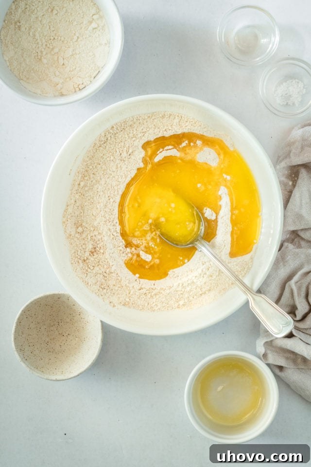 Overhead view of melted butter being stirred into the dry crumb topping mixture.
