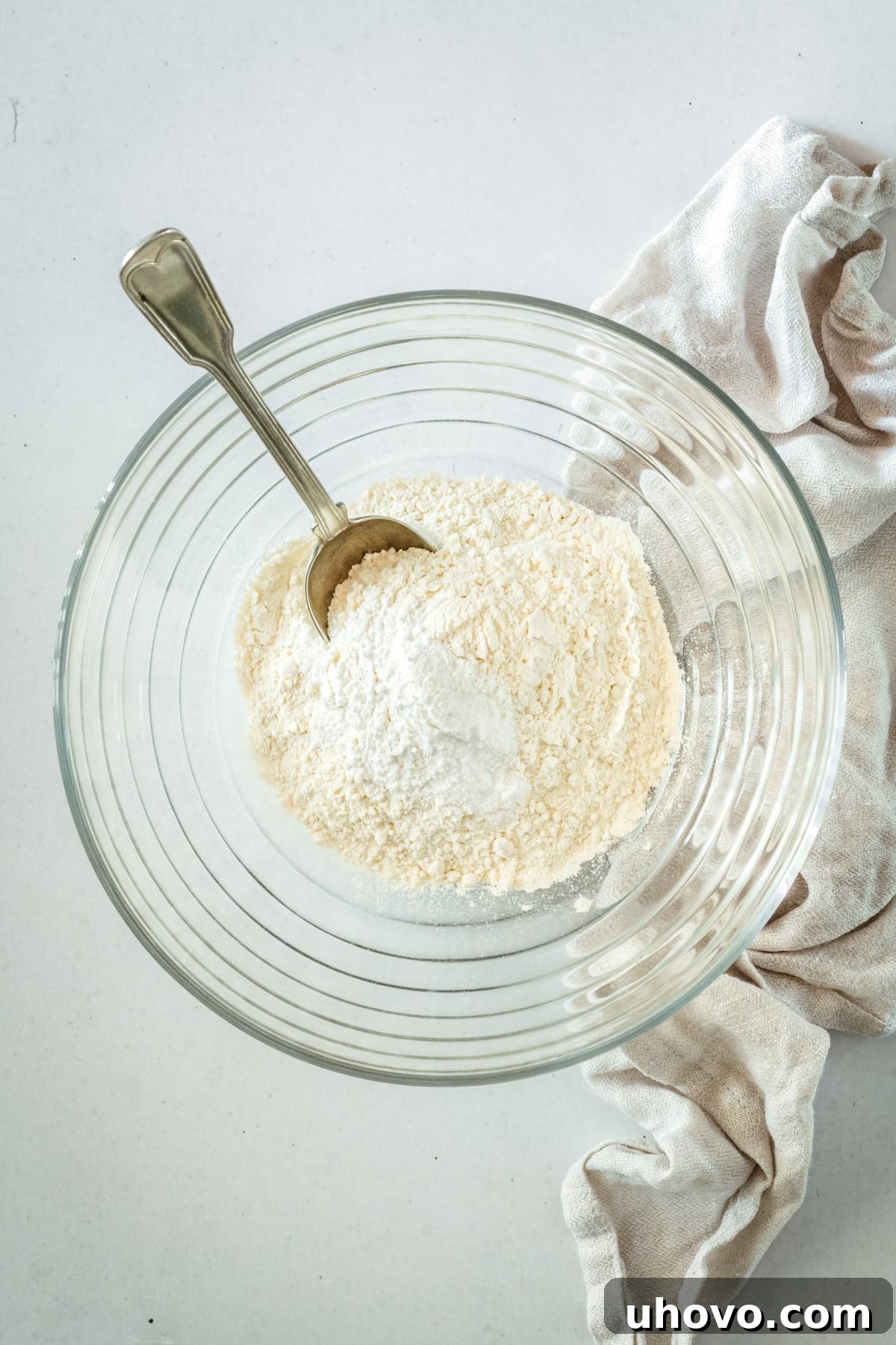 Overhead view of dry coffee cake ingredients in a glass mixing bowl, whisked together.
