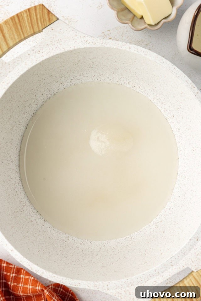 Granulated sugar and water heating in a heavy-bottomed saucepan, beginning the caramelization process for the topping.