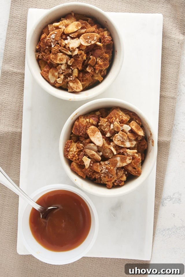 Overhead view of Cinnamon Almond Bread Pudding for Two with a bowl of salted caramel on a marble tray, ready to be served.