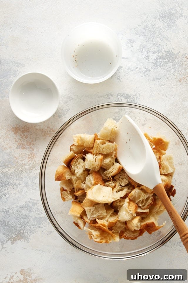 Overhead view of the croissant mixture for bread pudding, with cubed croissants, almonds, and almond paste combined in a bowl.