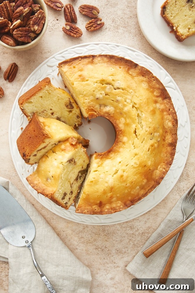 Overhead view of a perfectly golden Cream Cheese Pound Cake on a white cake plate, ready to be sliced.