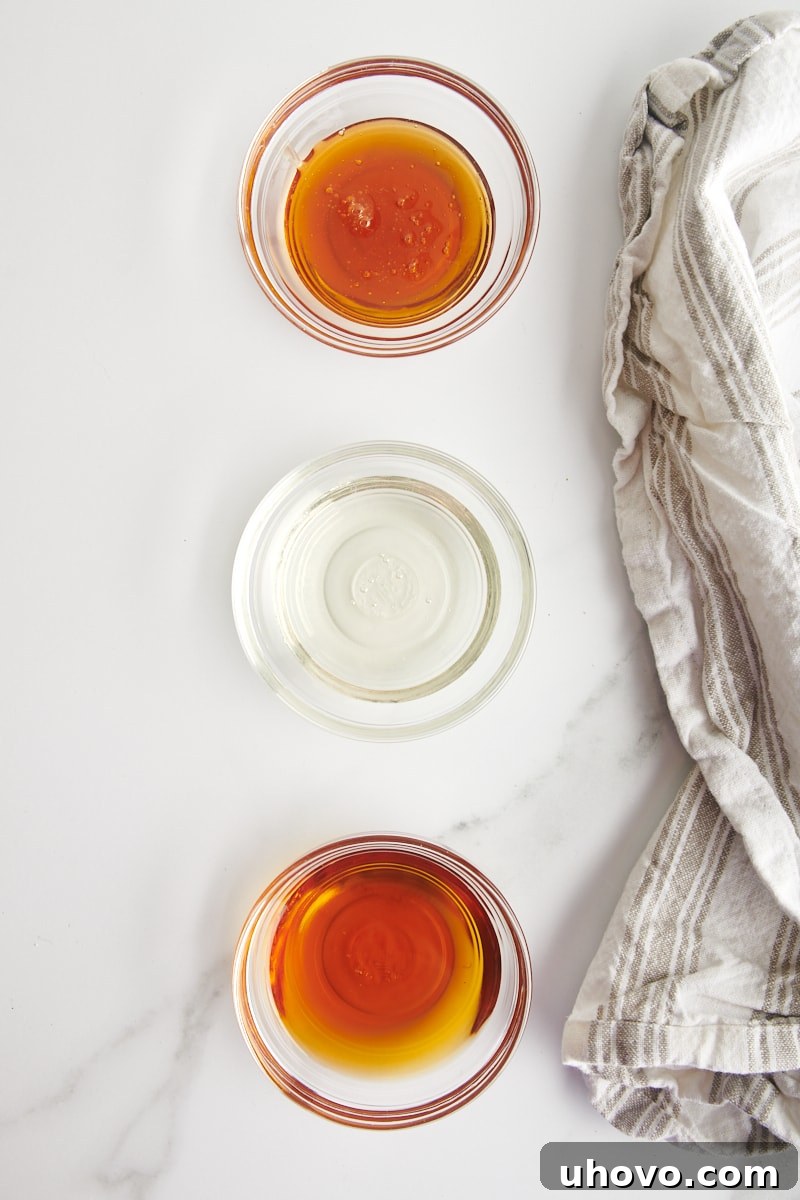 overhead view of honey, corn syrup, and maple syrup in small glass bowls