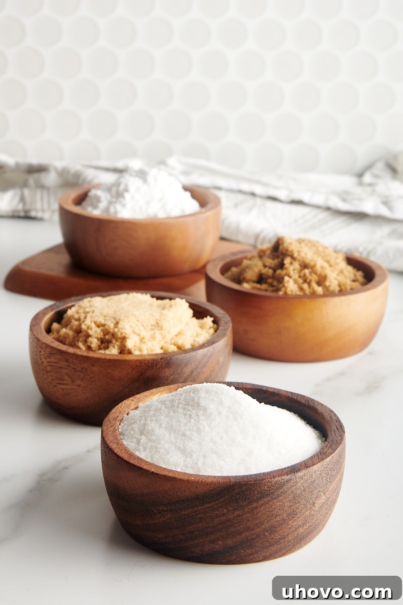 granulated sugar, light brown sugar, dark brown sugar, and confectioners' sugar in small wooden bowls