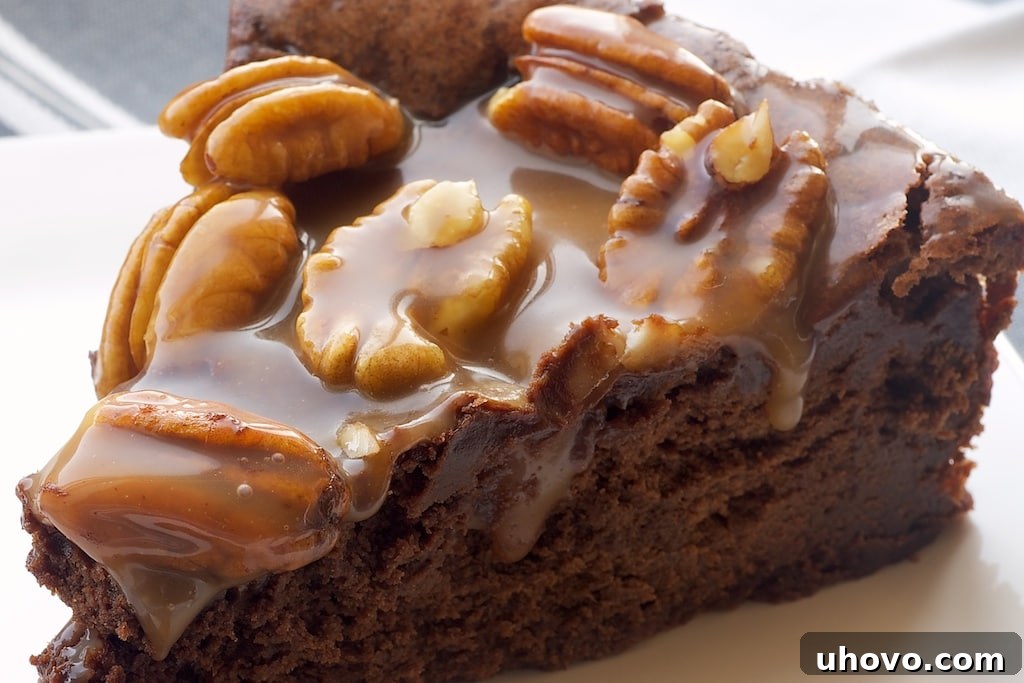 Close-up of a rich Chocolate Caramel Pecan Souffle Cake on a vintage plate, showing its moist texture and the generous, glossy caramel pecan topping.