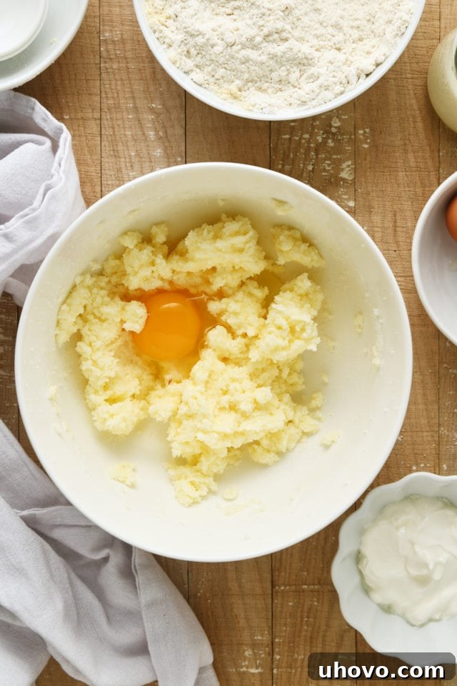 Overhead view of a cracked egg being added to the wet ingredients mixture for Almond Crumb Cake.