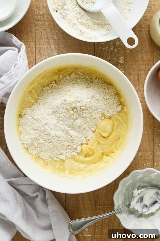 Overhead view of dry ingredients being gradually added to the wet ingredients for Almond Crumb Cake.