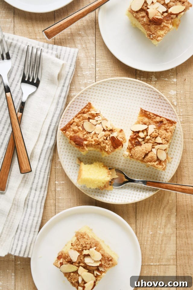 Several inviting slices of Almond Crumb Cake served on elegant white plates.