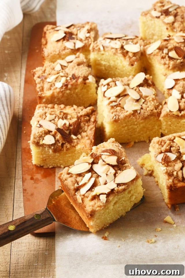 Several beautiful slices of Almond Crumb Cake arranged on a rustic wooden cutting board.