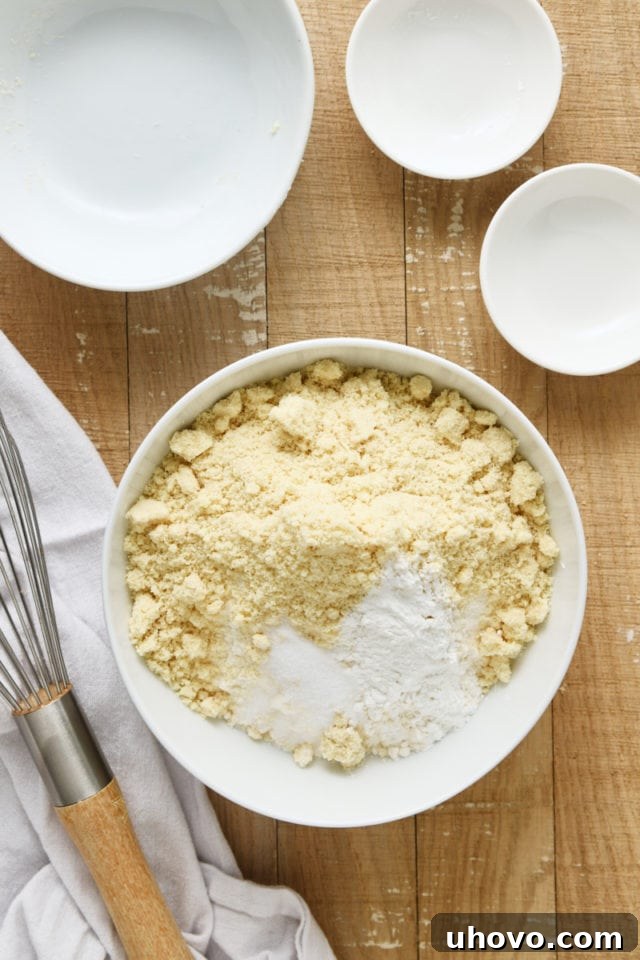 Overhead view of flour, almond flour, baking powder, and salt in a white mixing bowl before whisking.