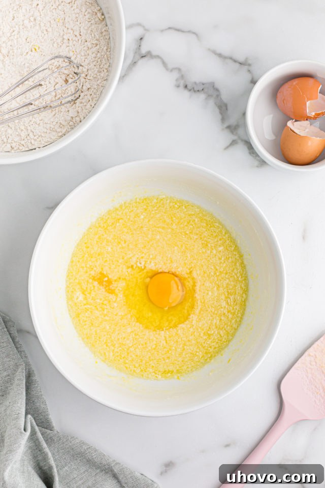 Overhead view of egg cracked into mixing bowl of wet ingredients