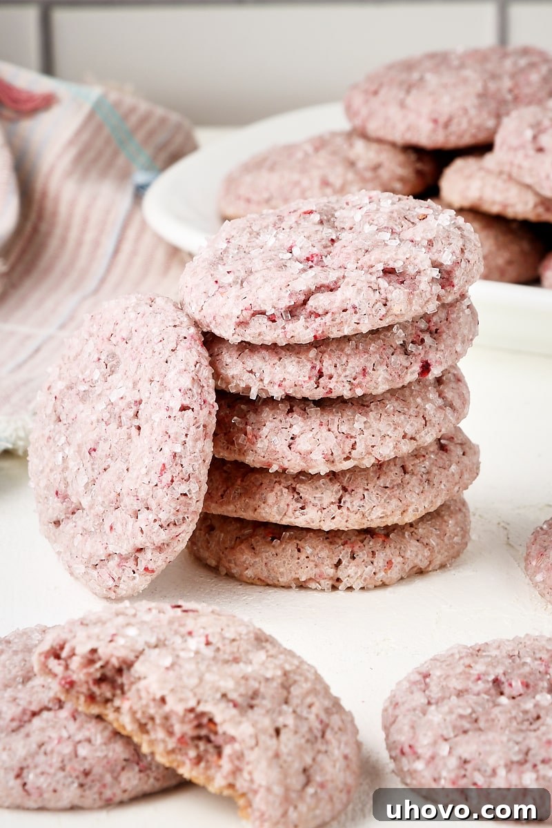 A perfectly stacked pile of raspberry sugar cookies, with more cookies artfully arranged around them.