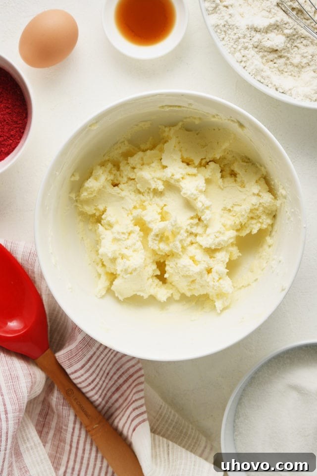 Overhead view of butter and cream cheese perfectly creamed together in a white mixing bowl, light and fluffy.