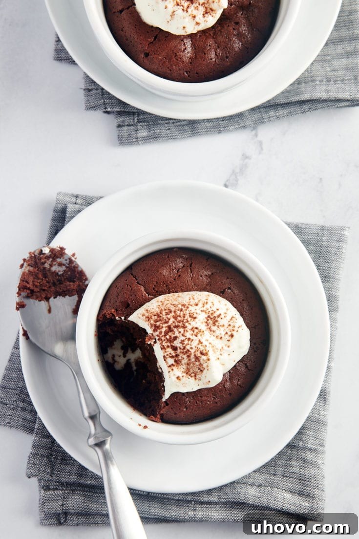 Warm Flourless Chocolate Cakes for Two topped with whipped cream, an intensely chocolatey small batch dessert.