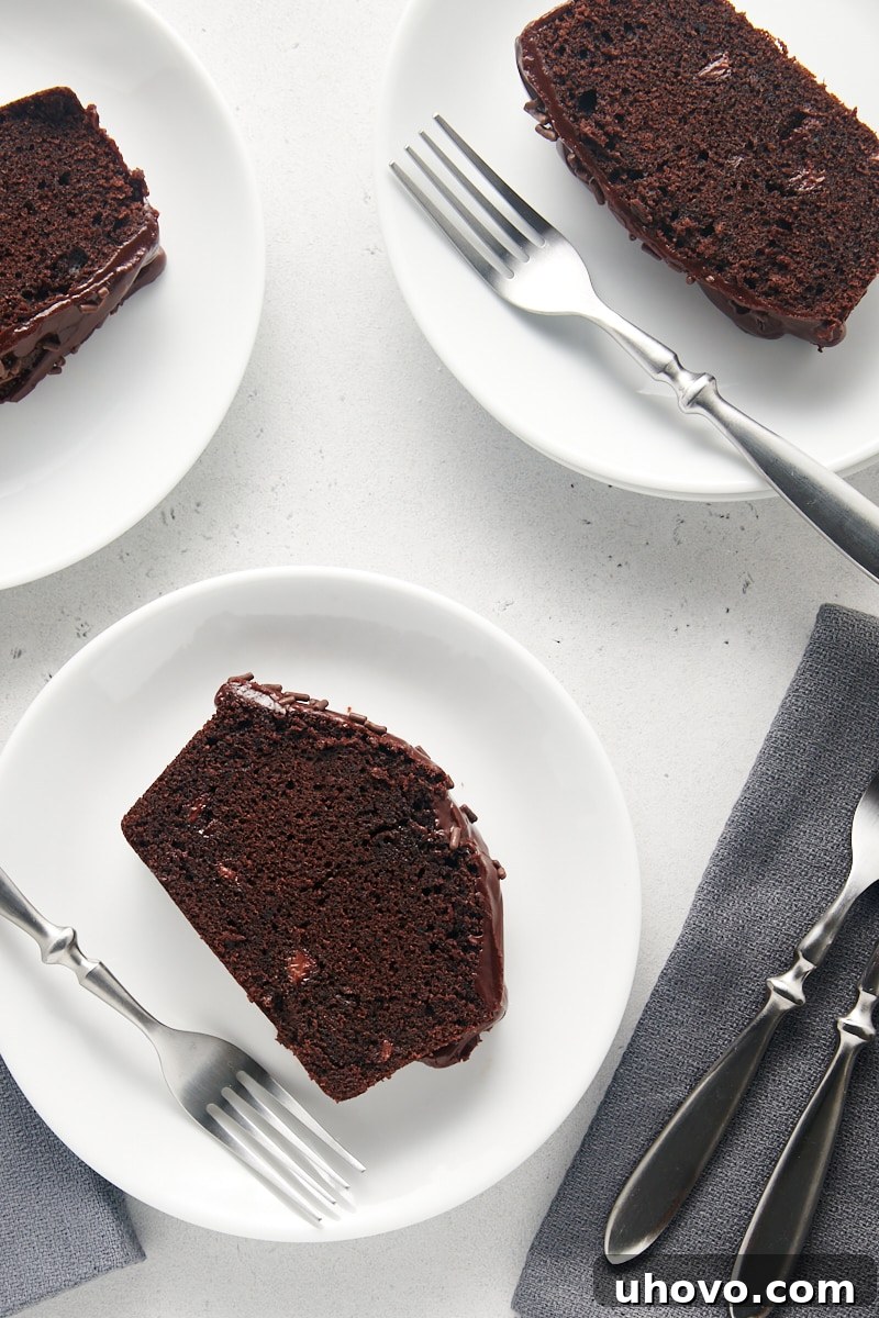 An artistic overhead arrangement of multiple slices of rich Chocolate Loaf Cake, each beautifully glazed, displayed on crisp white plates.