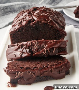 partially sliced Chocolate Loaf Cake on a white serving tray