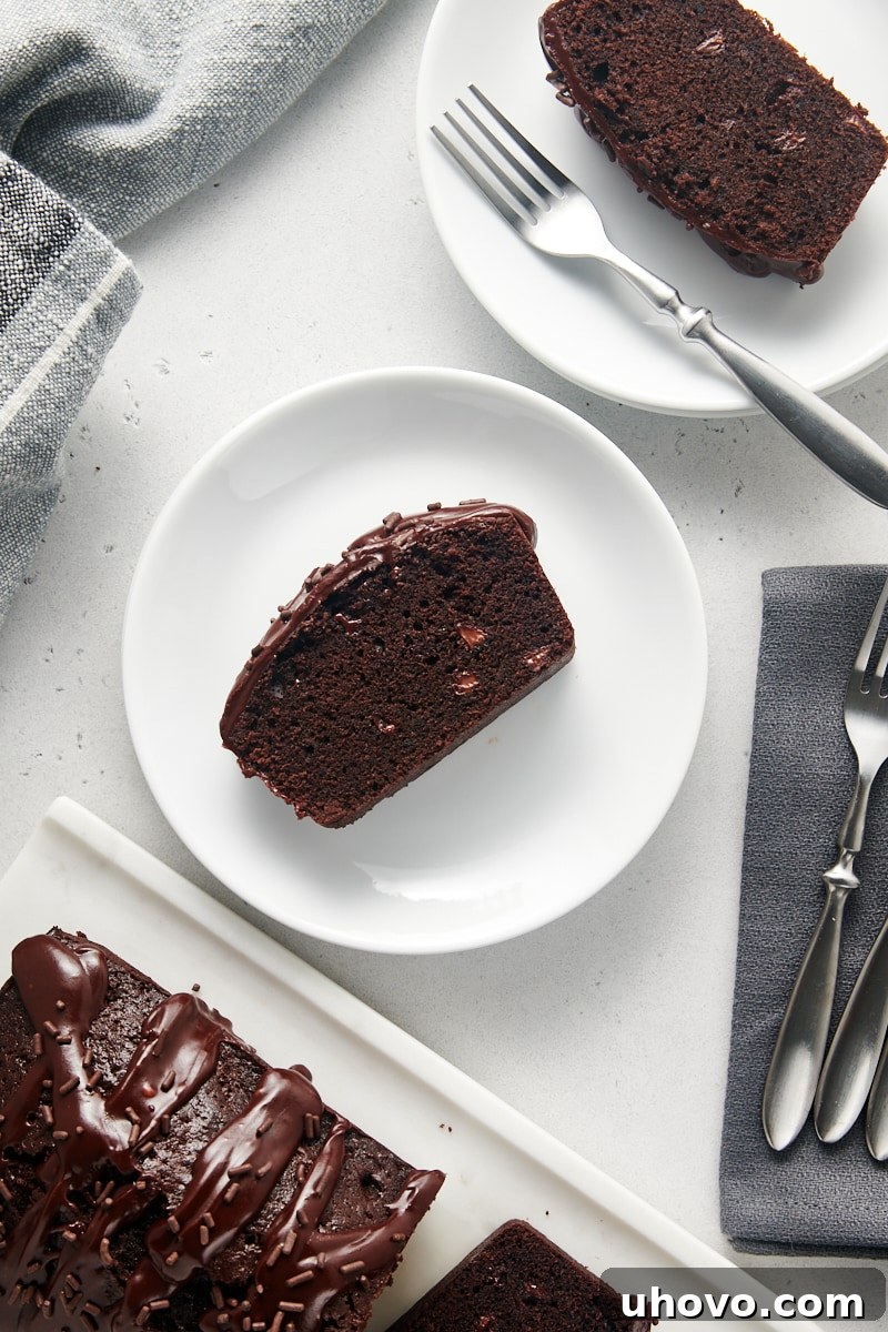 An overhead view of perfectly portioned slices of Chocolate Loaf Cake, each adorned with a generous chocolate glaze, arranged on white plates, inviting a delicious tasting.