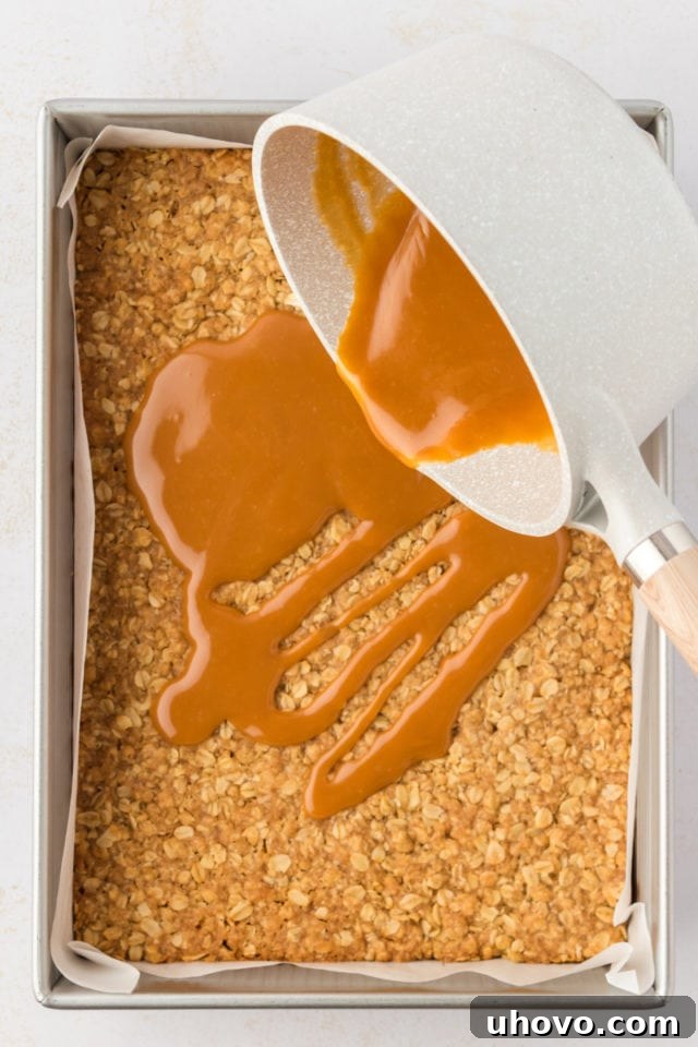 Overhead view of caramel being poured into pan over crust