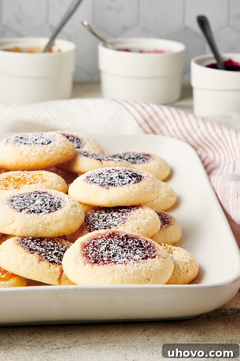 A bountiful pile of Cream Cheese Thumbprint Cookies arranged on a white serving tray, showcasing a delightful mix of jam fillings.