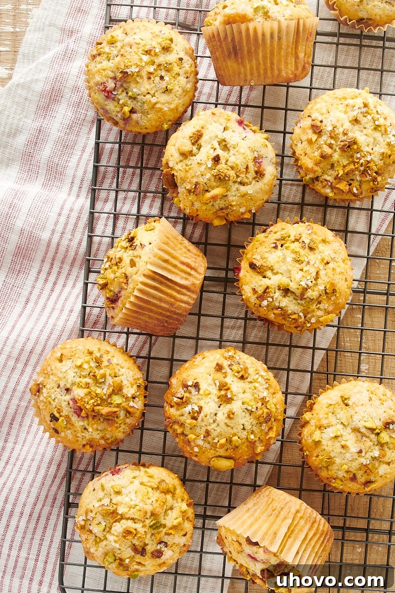 Overhead view of numerous Raspberry Pistachio Muffins cooling on a wire rack, showing their perfectly baked tops and inviting texture.