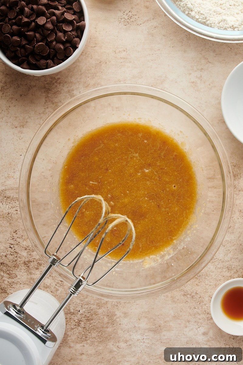 Overhead view of the mixed wet ingredients for Cheesecake-Stuffed Chocolate Chip Cookies in a glass bowl, showcasing a smooth and consistent batter.
