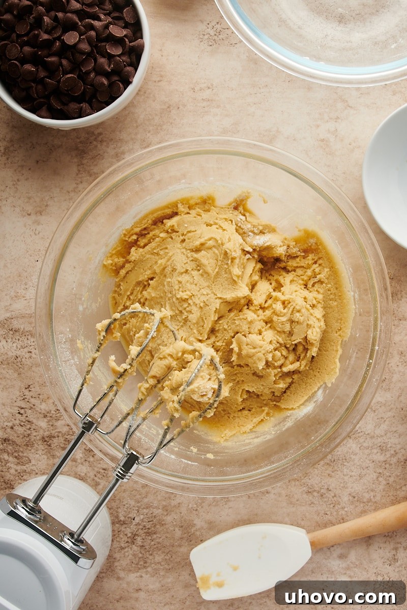Overhead view of the mixed Cheesecake-Stuffed Chocolate Chip Cookie dough in a glass bowl before adding chocolate chips.