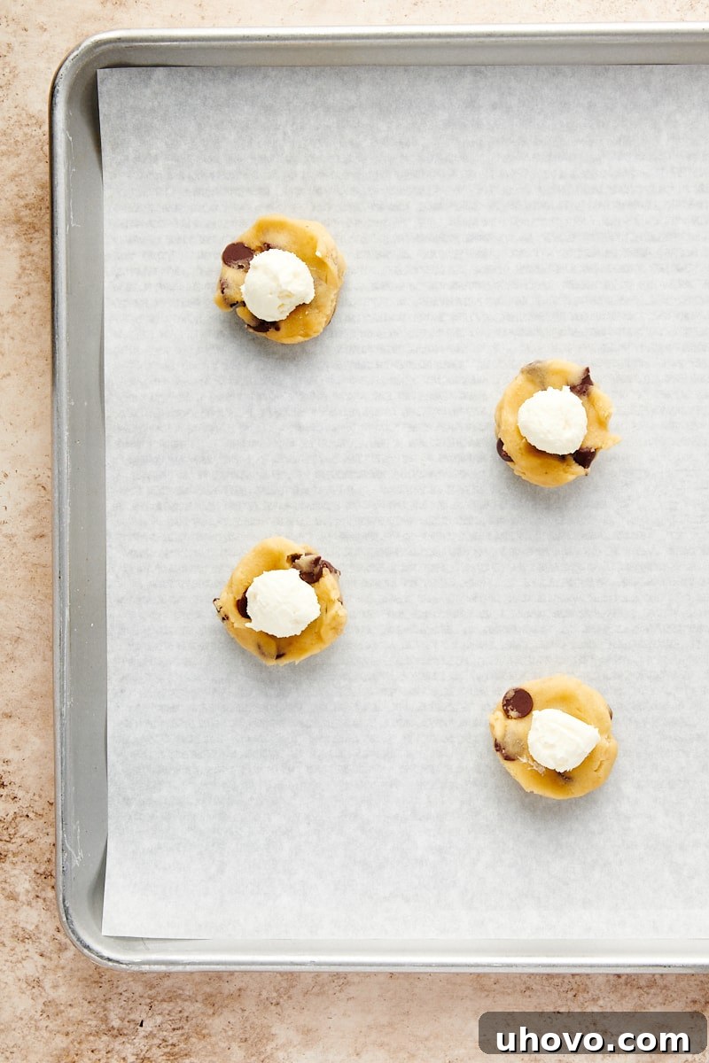 Overhead view of a portion of cookie dough with a dollop of creamy cheesecake filling placed precisely in its center.