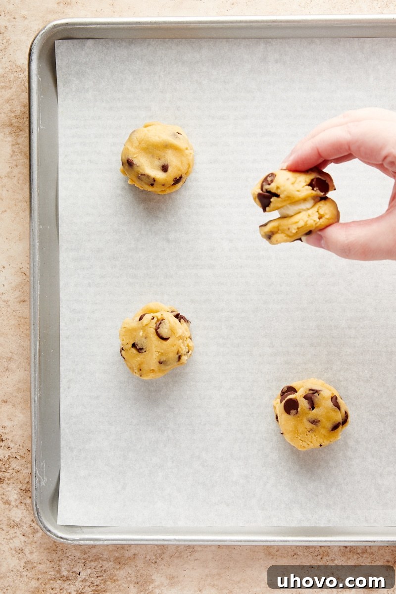 Overhead view of partially assembled Cheesecake-Stuffed Chocolate Chip Cookies, with the filling covered by another layer of dough but not yet fully sealed.