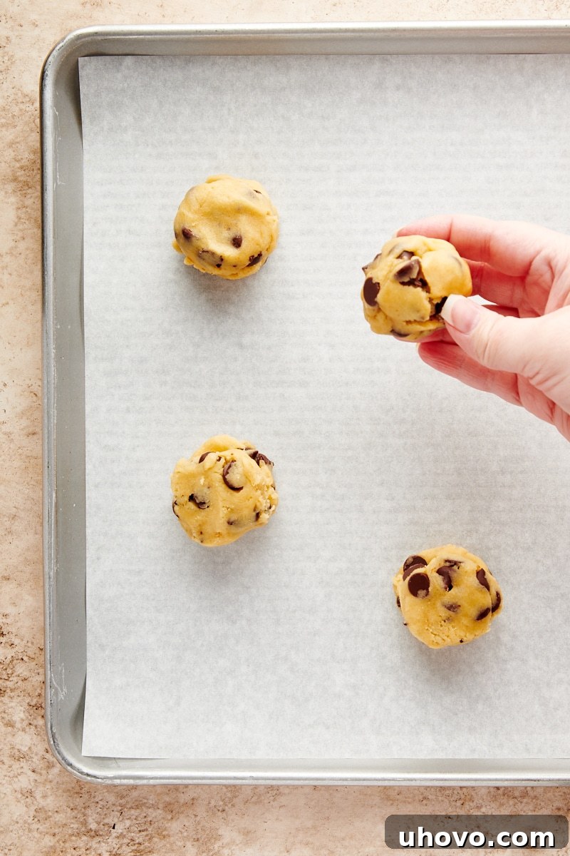 Overhead view of a perfectly rolled, ball-shaped Cheesecake-Stuffed Chocolate Chip Cookie dough, fully sealed and ready for baking.