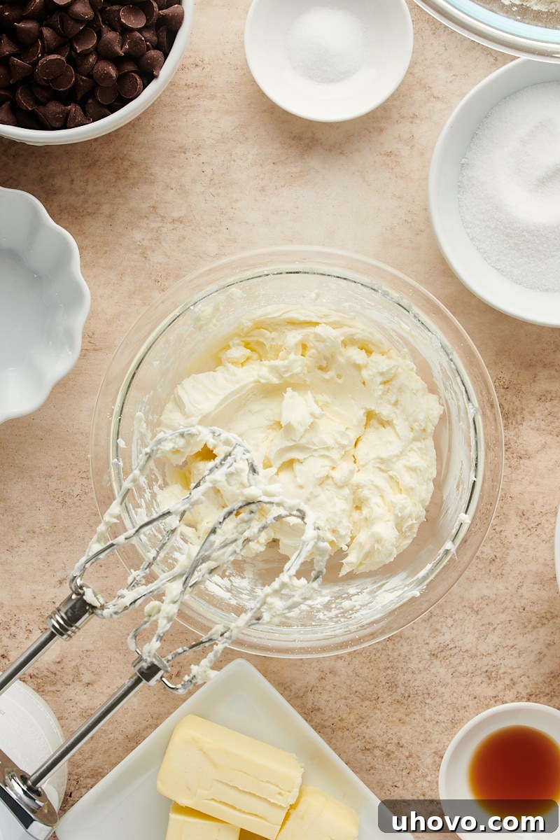 Overhead view of the smooth, white cream cheese filling in a glass mixing bowl after being beaten, showing a perfect consistency.