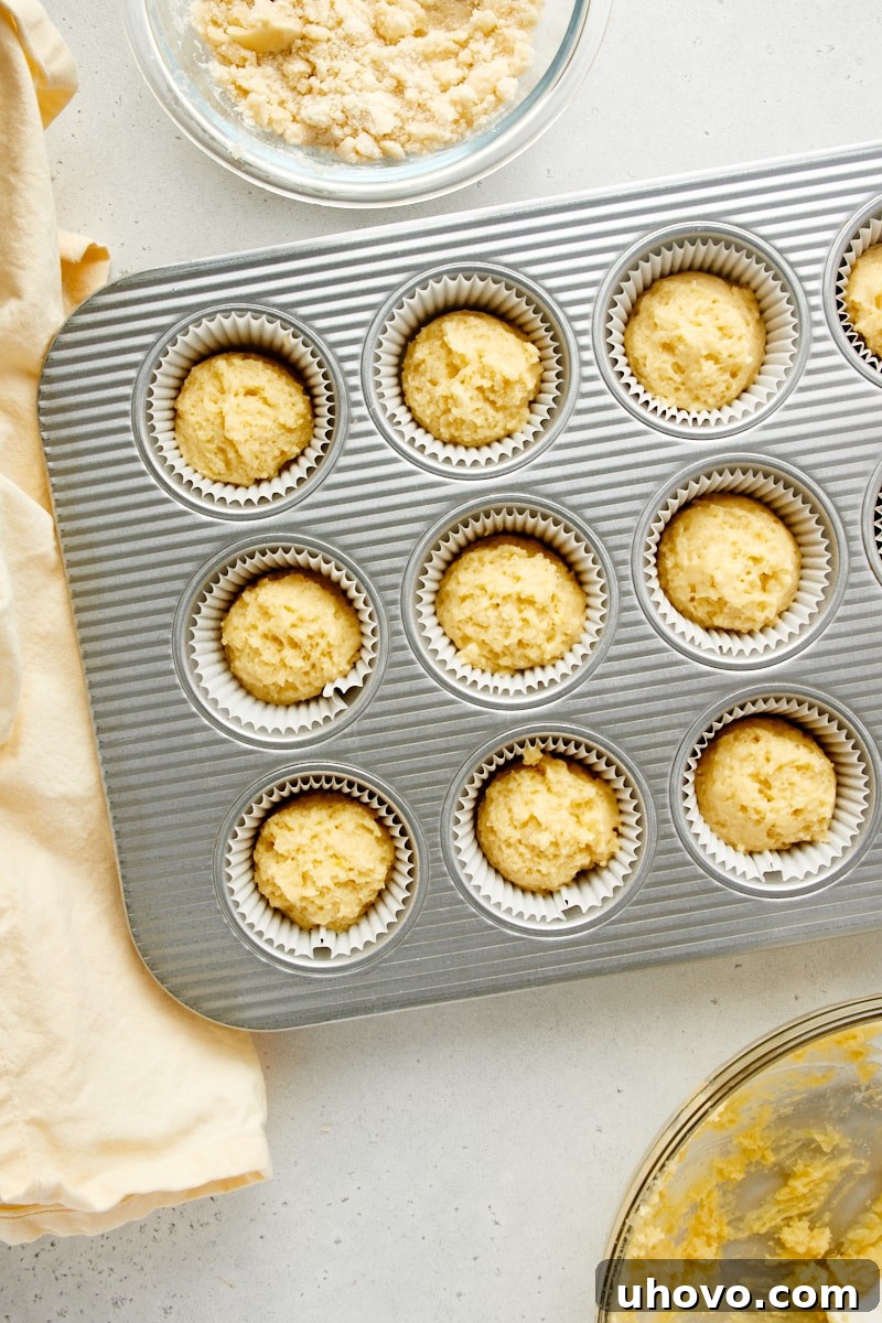 Overhead view of lemon muffin batter neatly portioned into a 12-cup muffin pan.