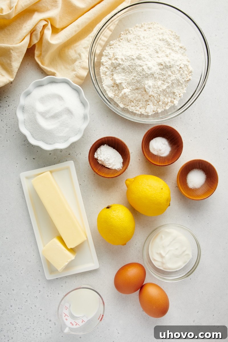 Overhead shot of fresh ingredients laid out on a white surface, ready for making Lemon Crumb Muffins.