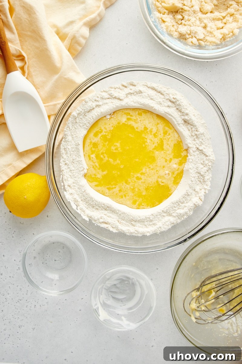 Overhead view of wet ingredients being poured into the well of dry ingredients for Lemon Crumb Muffins.