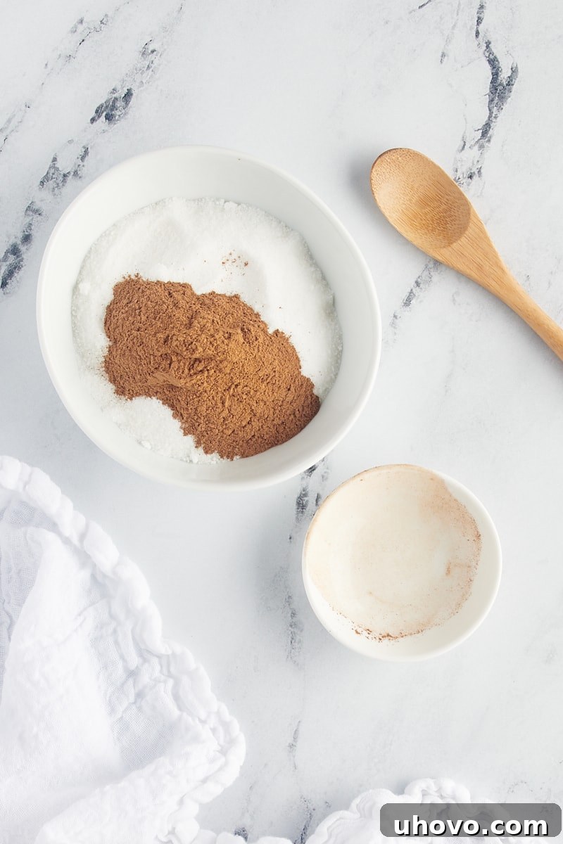 overhead view of cinnamon added to sugar in a white bowl