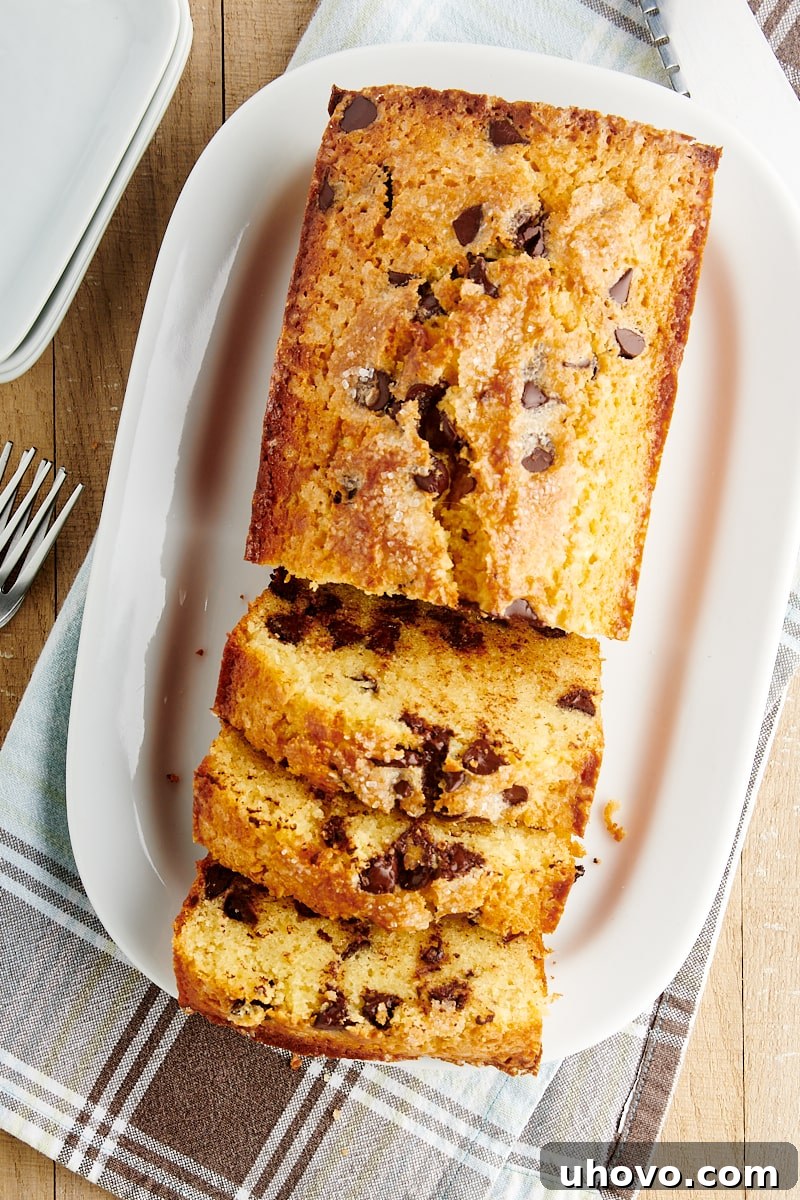 Overhead view of a perfectly sliced Chocolate Chip Loaf Cake on a white serving tray, ready to be enjoyed