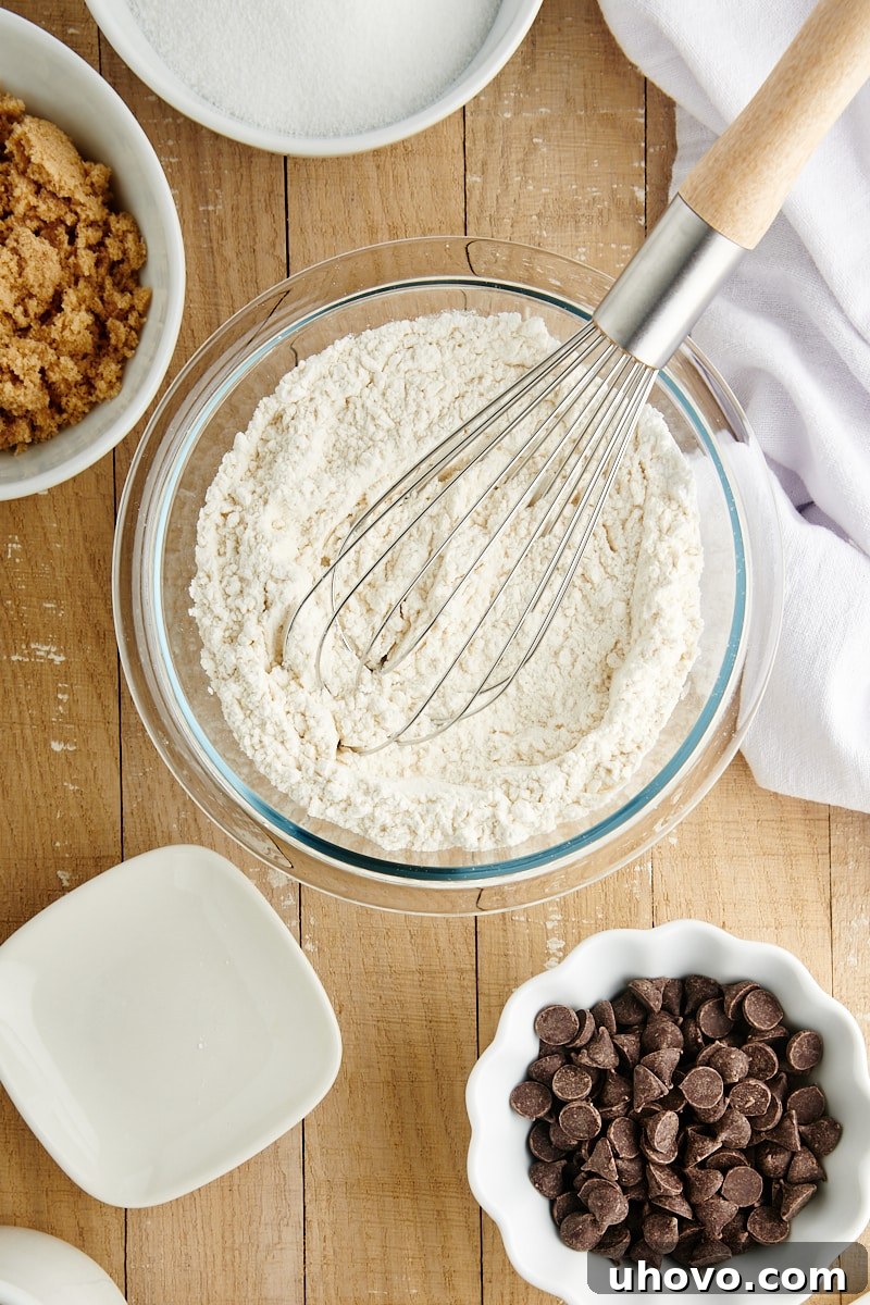 Overhead view of dry ingredients for Chocolate Chip Loaf Cake, consisting of flour, baking powder, and salt, mixed in a glass bowl