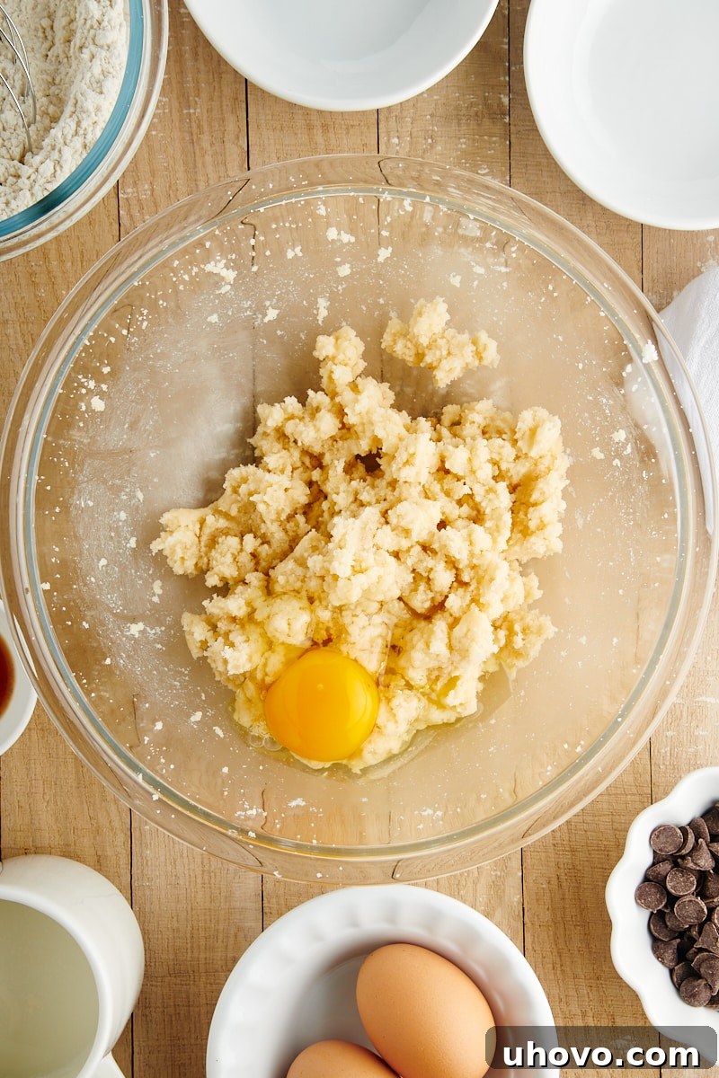 Overhead view of wet ingredients for Chocolate Chip Loaf Cake, showing beaten butter and sugars, with eggs and vanilla extract partially mixed in