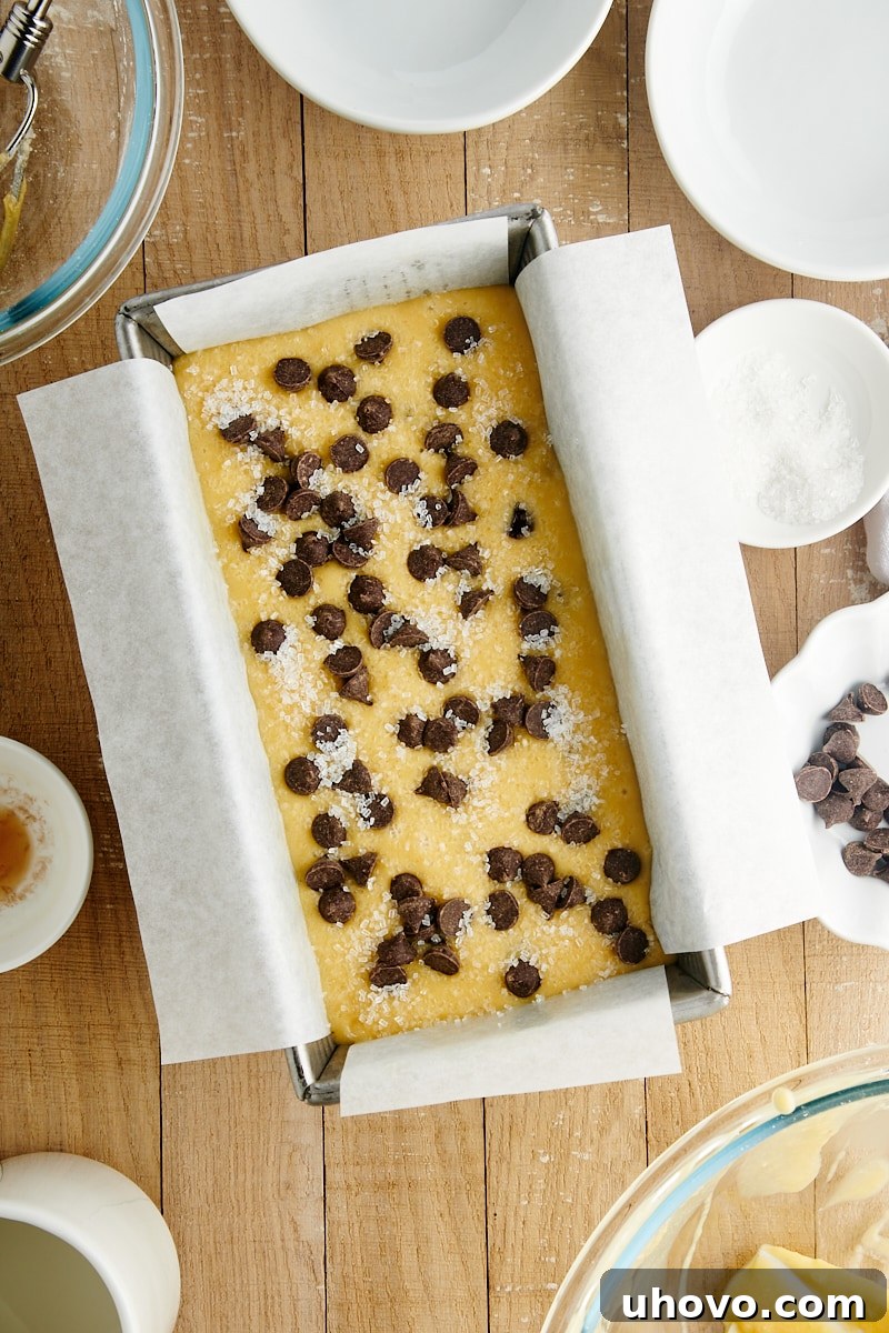 Overhead view of the Chocolate Chip Loaf Cake batter spread evenly in a parchment-lined loaf pan, ready for baking