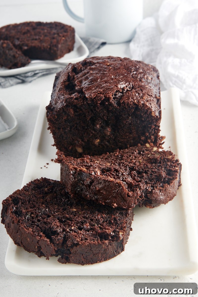 A beautifully sliced loaf of moist Chocolate Zucchini Bread on a white serving tray, ready to enjoy.