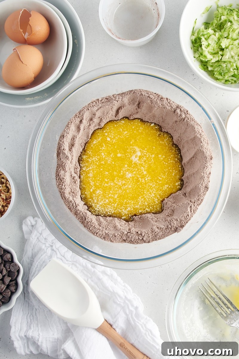 An overhead view showing the wet ingredients being poured into the well of the dry ingredients for Chocolate Zucchini Bread.