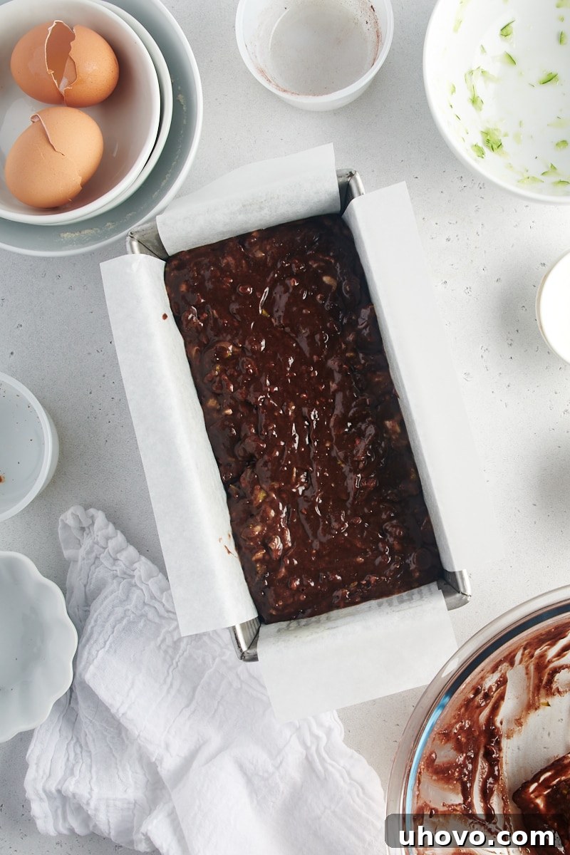 An overhead view of Chocolate Zucchini Bread batter poured into a parchment-lined loaf pan, ready for baking.